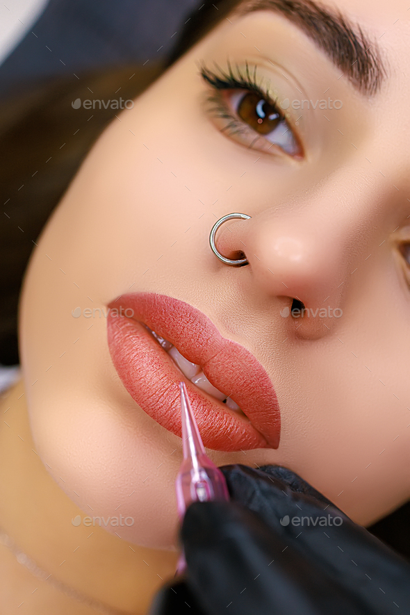 Close-up model\'s lips performed with permanent lip makeup. Lip tattoo work after tattoo.