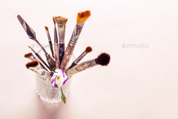 Art brushes and flowers in glass on table. Selective focus Stock Photo by  colnihko