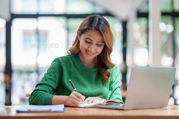 Beautiful young Asian woman student are reading book and taking notes ...