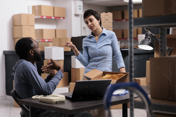 Diverse employees discussing transportation logistics while preparing packages