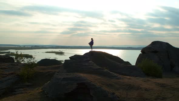 A Girl is Doing Fitness on a Hill on the Lake Shore