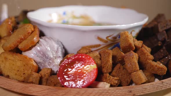Salt falling on a plate with soup, bread crackers and fresh vegetables alt