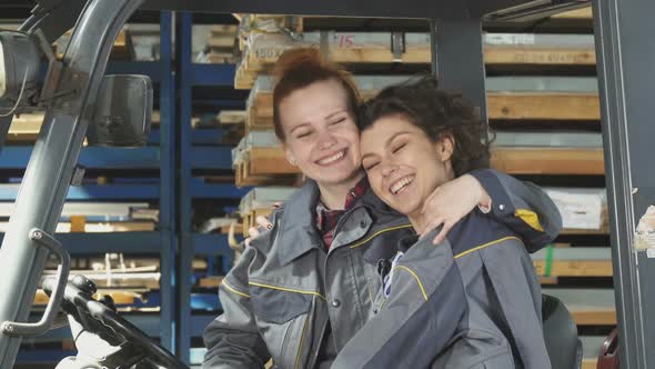 Two Cheerful Female Factory Workers Hugging Smiling Happily To the Camera alt