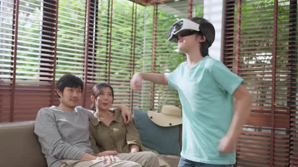 asian family son wear VR or virtual reality glasses,headsets standing and playing a video game