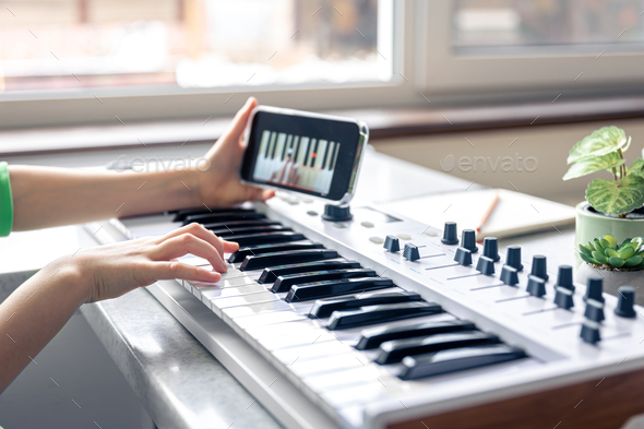 The child learns to play the piano with a smartphone, online music lesson.