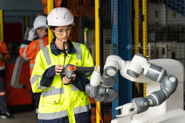 Female Engineer check and control automation robot arms machine in factory. robotics manufacturing.