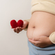 Mother hands carrying knitted heart shape at tummy showing concept of pregnancy. - PhotoDune Item for Sale