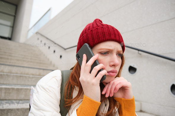 Portrait of worried girl calls somebody with concerned face, being on a phone, receives bad news