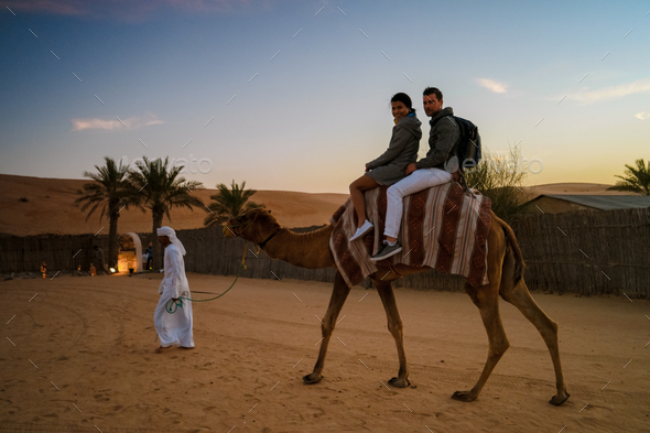 Couple riding a camel during Dubai desert safari at the safari camp, Dubai United Arab Emirates