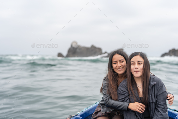 Friends embracing while sitting on a boat in the middle of the sea