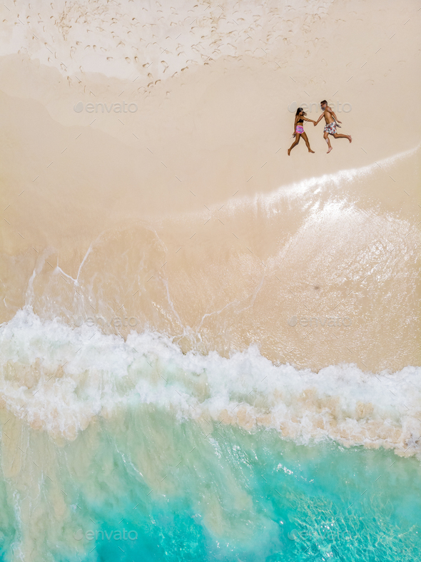 Drone view from above at a tropical beach with men and woman laying ...