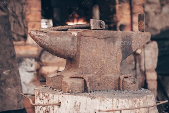 Process metal with hammer on anvil in forge. Strike iron outdoors in workshop with fire
