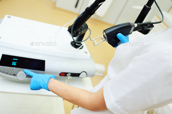 cosmetologist holds a CO2 fractional ablative laser for skin rejuvenation and scar removal in his
