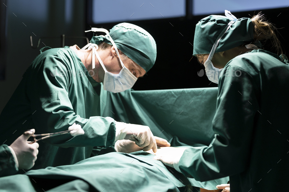 Surgeon operating on patient, team of medical professionals working in operating room. - Stock Photo - Images
