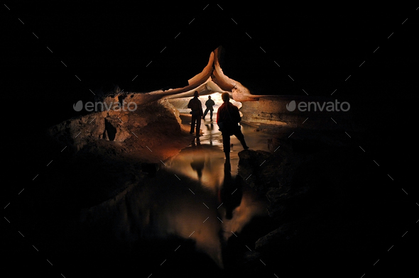 Spelunkers exploring an underground cave river - Stock Photo - Images