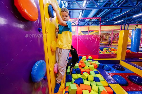 Happy kids playing at indoor play center playground, brothers climbs in ...