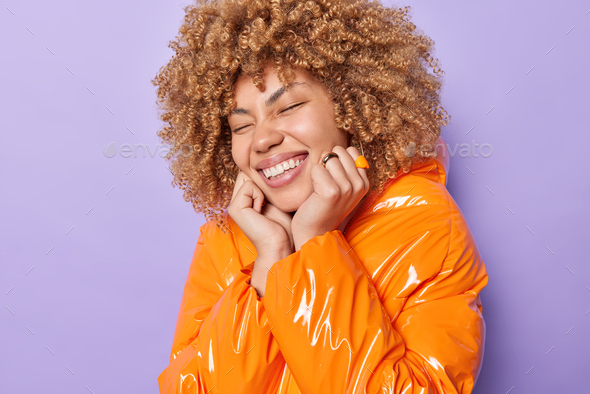 Overjoyed Curly Haired Woman Keeps Eyes Closed Smiles Broadly Keeps