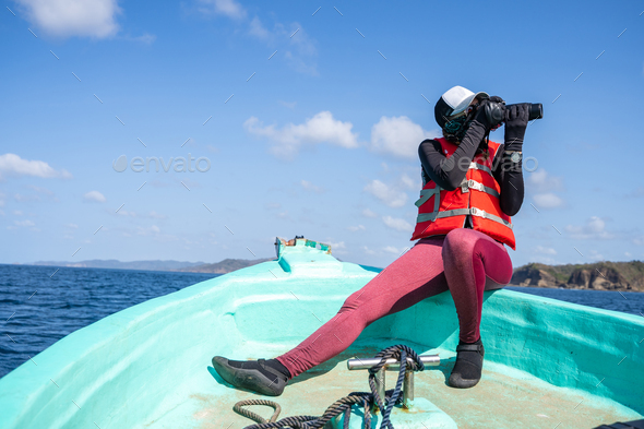 Female marine biologist taking photos while working on a boat