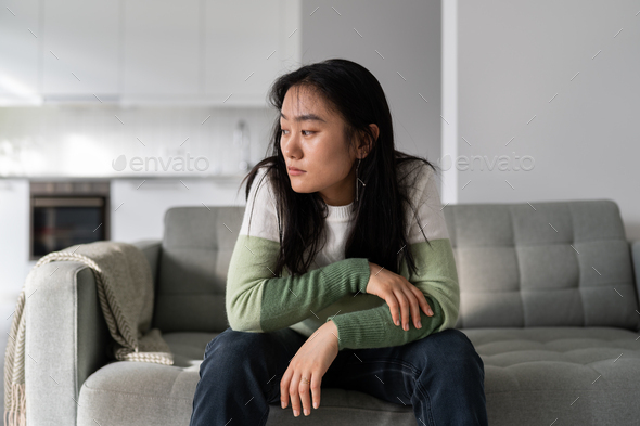 Sad lonely young Asian woman having depression symptoms worrying about money or family problems