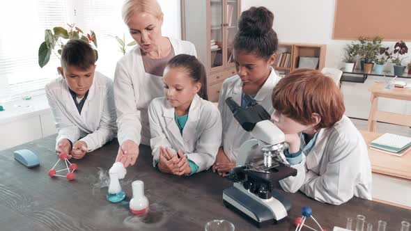 Female Teacher Showing Experiment to Schoolchildren in Science Class alt