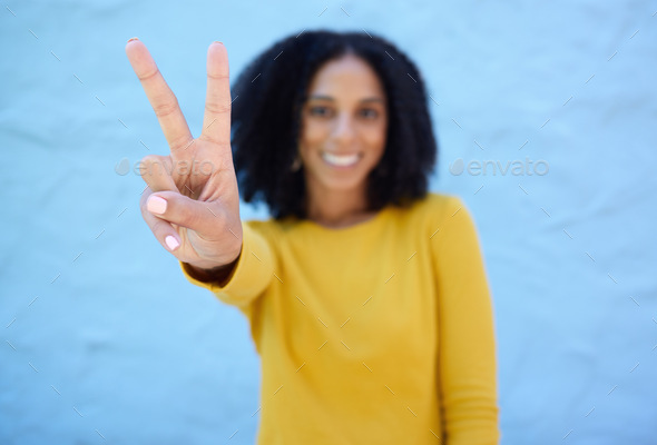 Black woman, hand and peace sign for victory, win or letter V against a blue wall background on moc