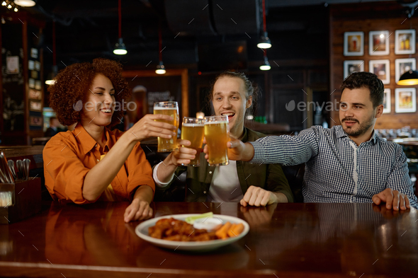 Cheerful old friends having fun and drinking draft beer in sports bar
