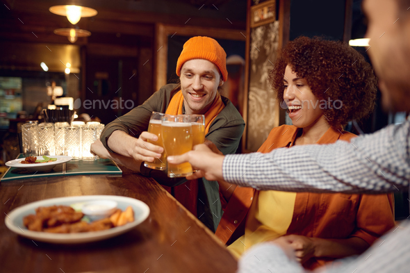 Happy friends drinking beer while rest sitting at bar counter desk