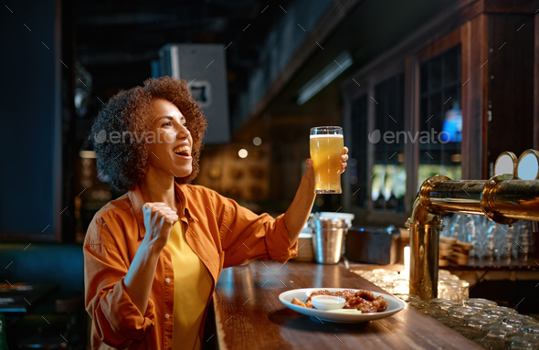 Young woman cheering for favorite team watching match in sports bar
