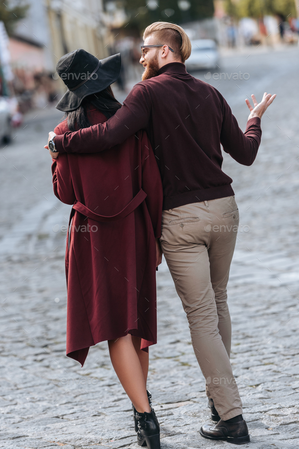 back view of stylish couple walking at old european city