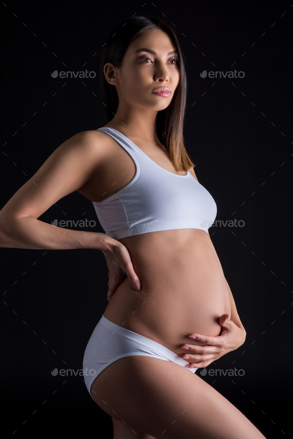 asian pregnant woman posing in white underwear, isolated on black