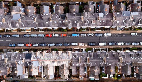 Aerial view directly above the rooftops and gardens of a typical suburban street with parked cars