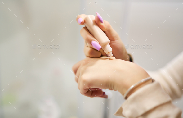 a teenage girl applying foundation on her hand to see the correct shade