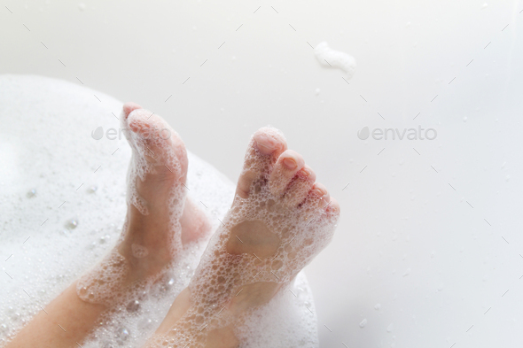Closeup of childs feet washing in bathroom with shampoo foam on it.