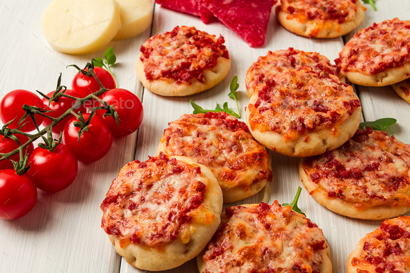 Mini pizzas, salami with mozzarella cheese, on a white table, top view ...