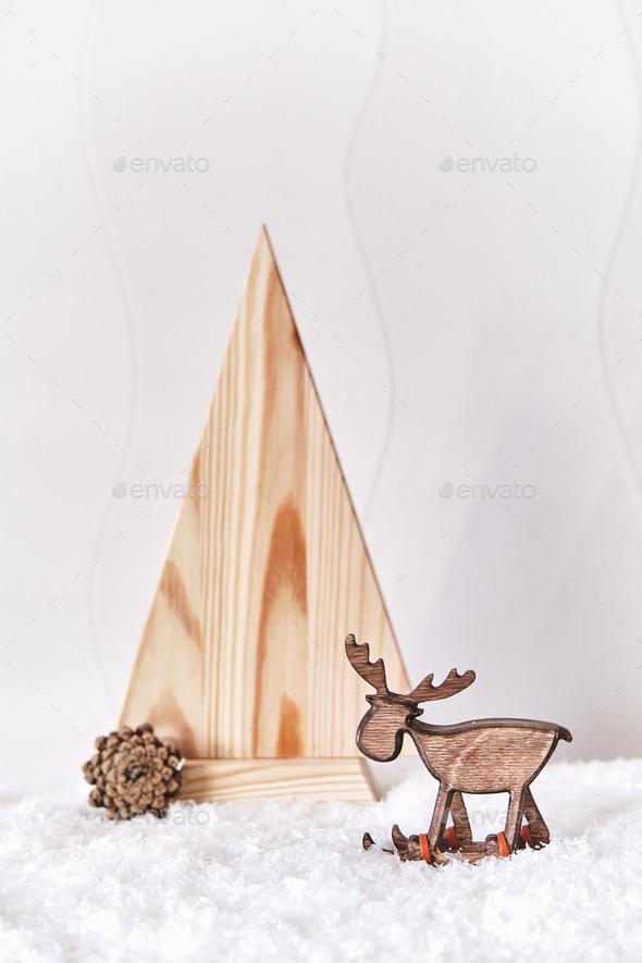 Christmas composition. Toy deer on skiing, wooden stylized Christmas tree, artificial snow