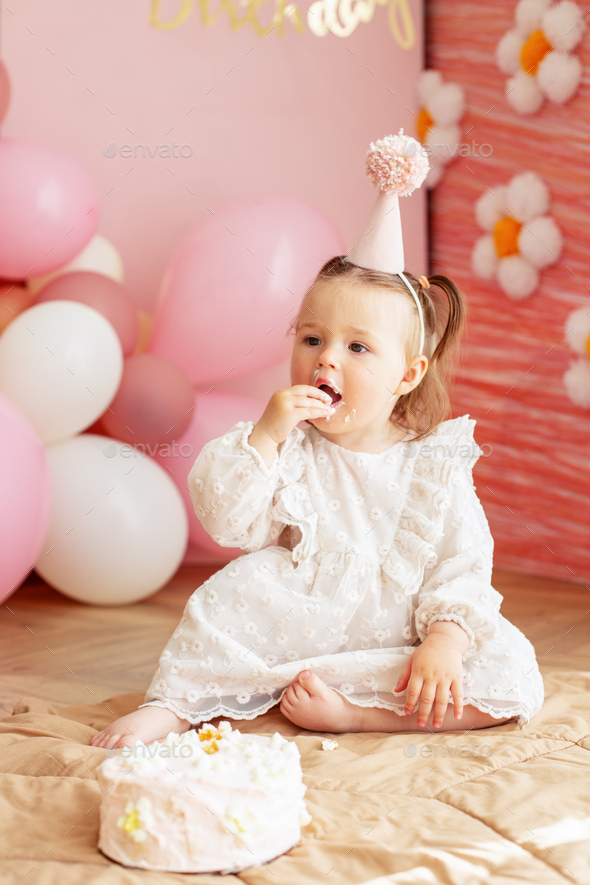 Young baby girl in pink holiday dress eating birthday cake with her hands  covered up her face with red icing sitting on the table in party hat Stock  Photo  Alamy