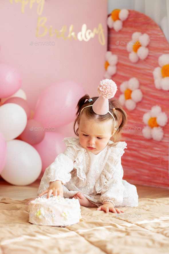 Cute baby eating cake for first birthday. Baby girl in dress. Festive decor  in pink colors Stock Photo by OlhaRomaniuk