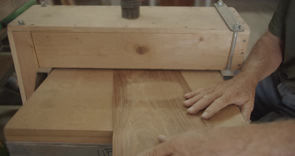 Old hands pushing wood through a filler