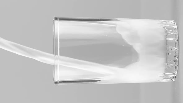 Vertical Video Milk Pouring Into Glass Close Up Isolated on Light Grey Background