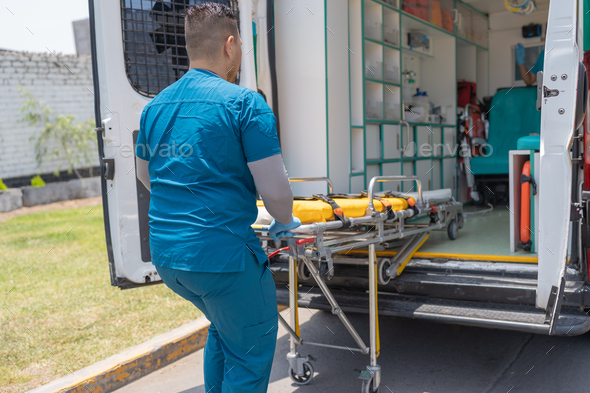 Medical personnel pulling a stretcher out of an ambulance. Stock Photo ...