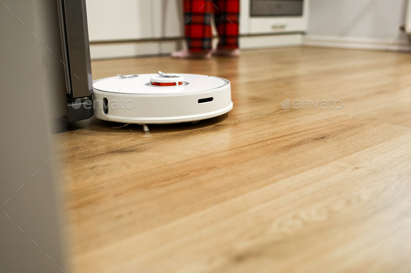 robot vacuum cleaner works while the girl is cooking in the kitchen