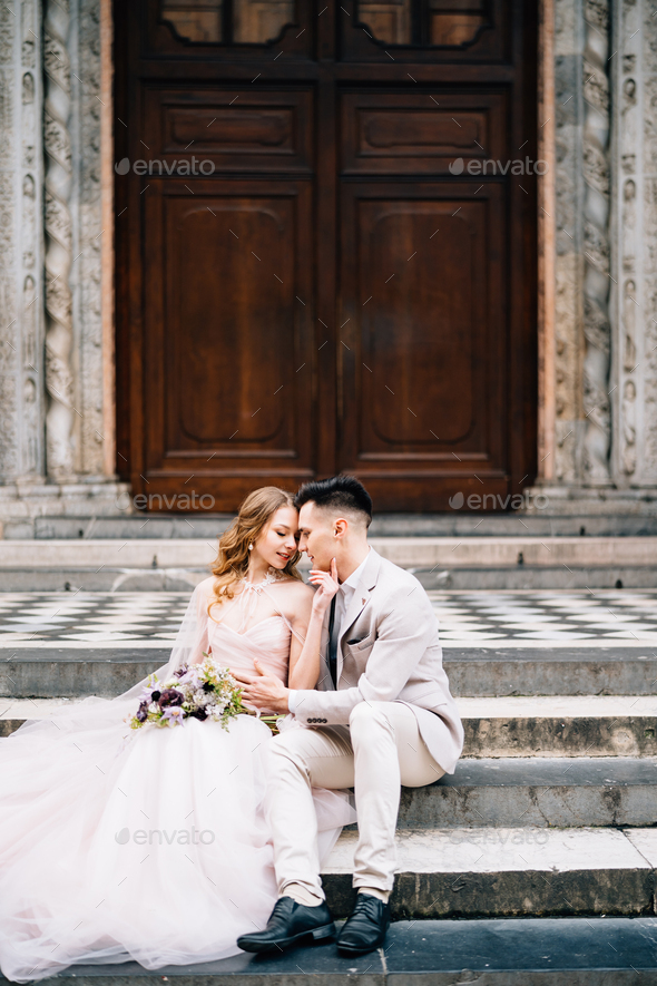 Bride and groom are hugging each other on the steps at the entrance to the Basilica of Santa Maria