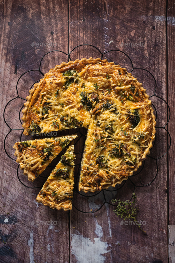Top down view of a delicious broccoli quiche on wooden table, with piece cut out - Stock Photo - Images