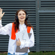 Cheerful student girl greeting friends by waving hand at collage outside. - PhotoDune Item for Sale
