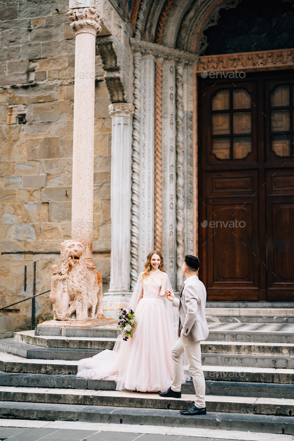 Bride and groom stand holding hands on the steps at the entrance to the Basilica of Santa Maria