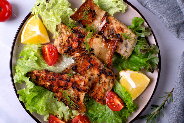 Grilled sturgeon pieces served with fresh lettuce, cherry tomato and lemon. Exquisite fish meal.