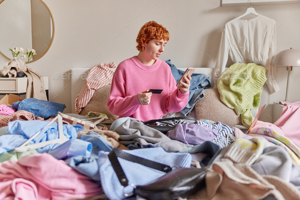 Indoor shot of serious redhead young woman poses on bed with carelessly ...