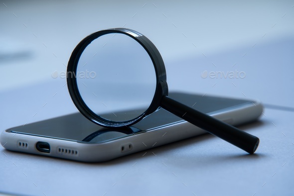 Magnifying glass over smart phone. SEO concept.
