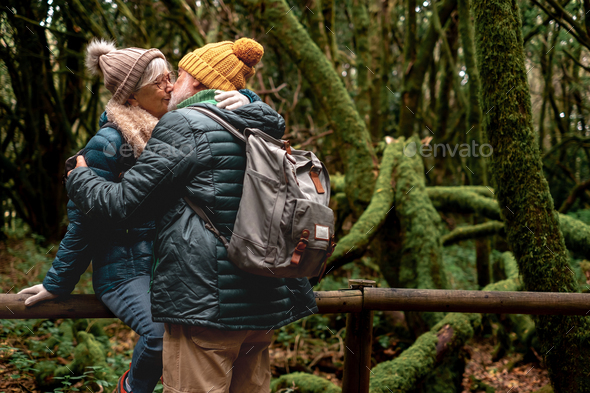 Beautiful senior couple enjoying nature outdoors in a mountain forest with moss covered trunks