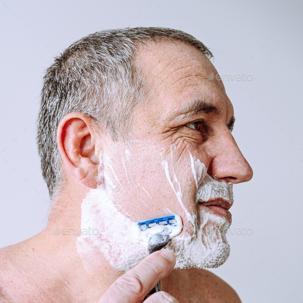 man shaves facial hair with disposable razor with safety blade Stock
